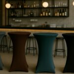 Stehtischhussen für Bars in Dunkelpetrol, Schokobraun und Schwarz in moderner Bar mit stilvoller Beleuchtung.