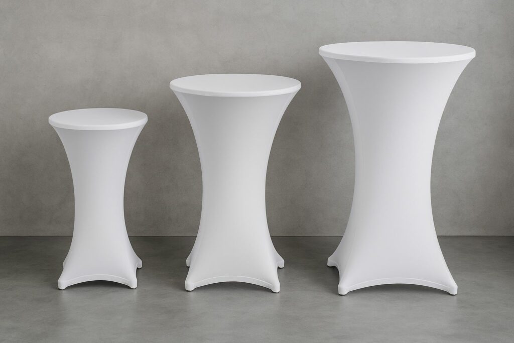 Stehtischhussen kaufen – drei Stehtische in unterschiedlichen Größen (60, 70 und 80 cm) mit weißen Stretchhussen in einem modernen Eventraum.