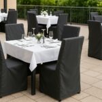 Outdoor-Restaurantbereich mit wetterfesten Hussen auf Tischen und Stühlen.