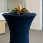 Navyblaue, weihnachtlich dekorierte Stehtischhusse mit Kerze und Tannenzweig im Büro.